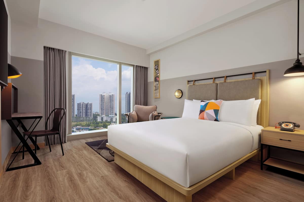 A modern hotel room with a large bed, a desk, and a chair.
