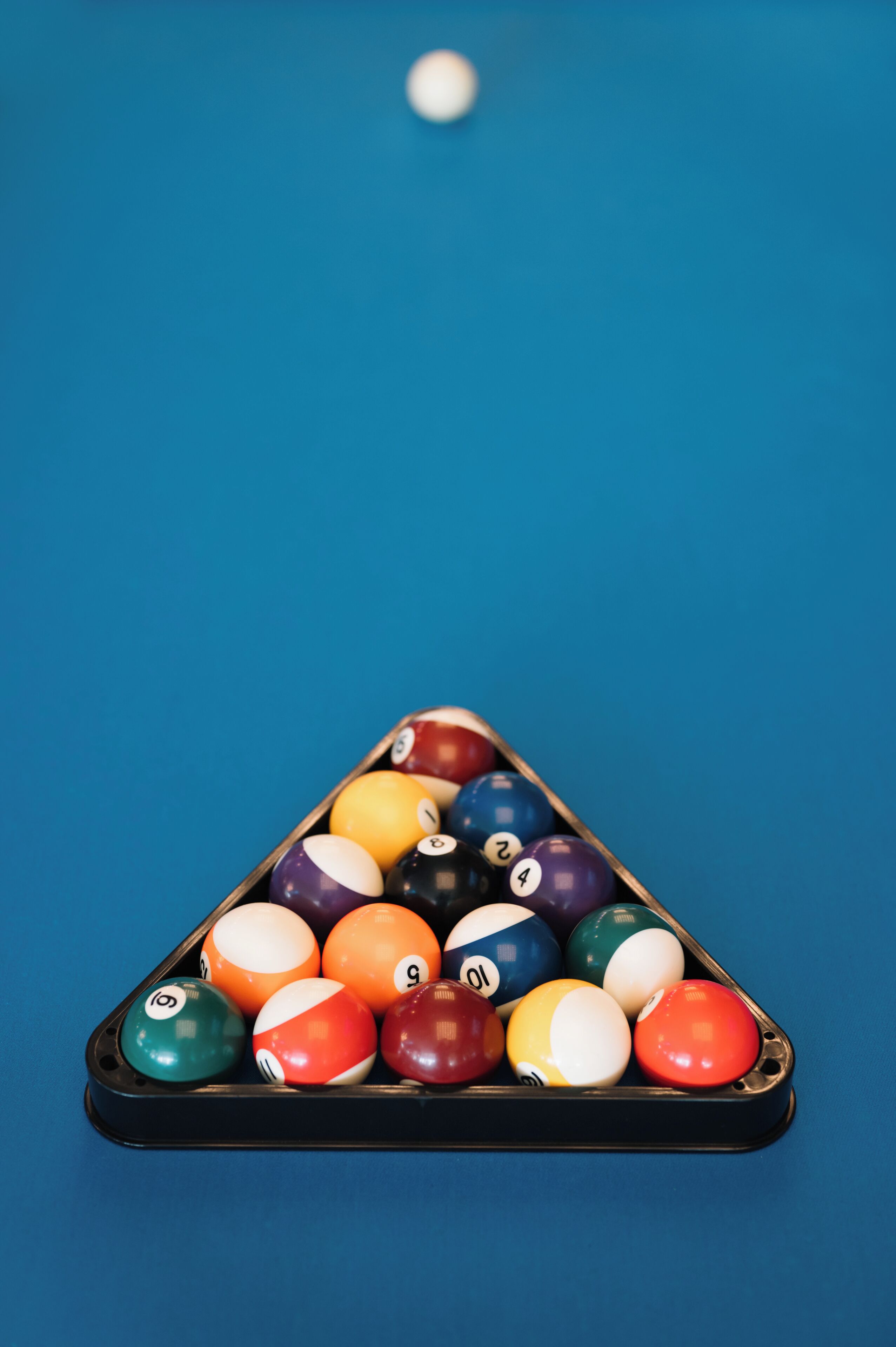 Una mesa de billar con un atril triangular lleno de bolas de billar.