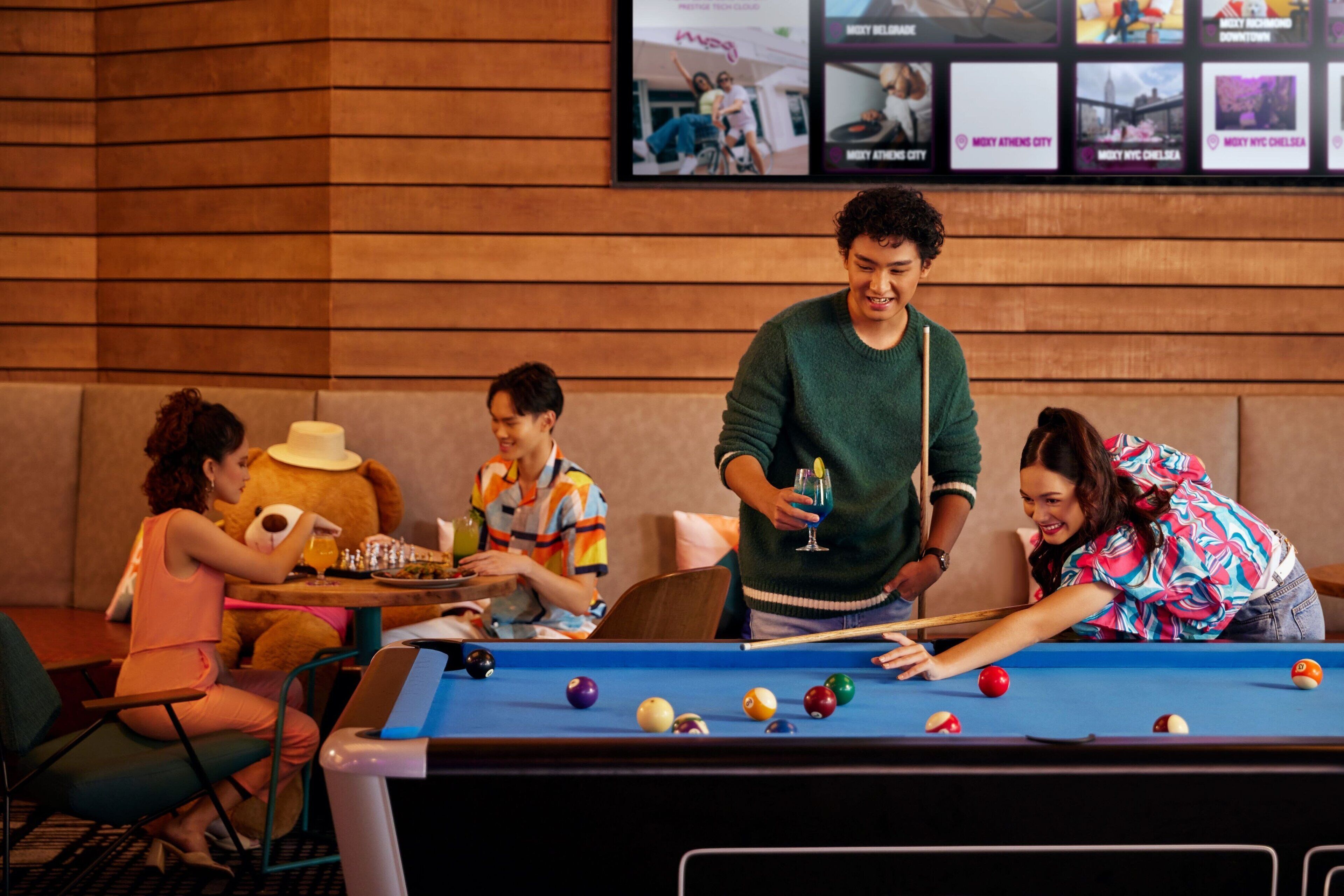 A pool table in a room with wooden paneling and a framed photo collage on the wall.