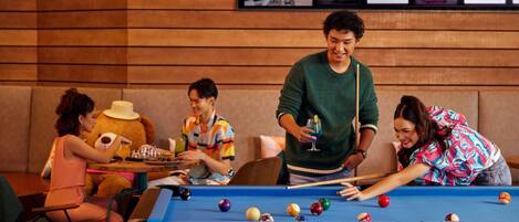 A pool table in a room with wooden paneling and a framed photo collage on the wall.
