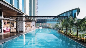 Una piscina interior moderna con agua azul cristalina, rodeada de exuberante vegetación y un edificio contemporáneo con amplios ventanales.