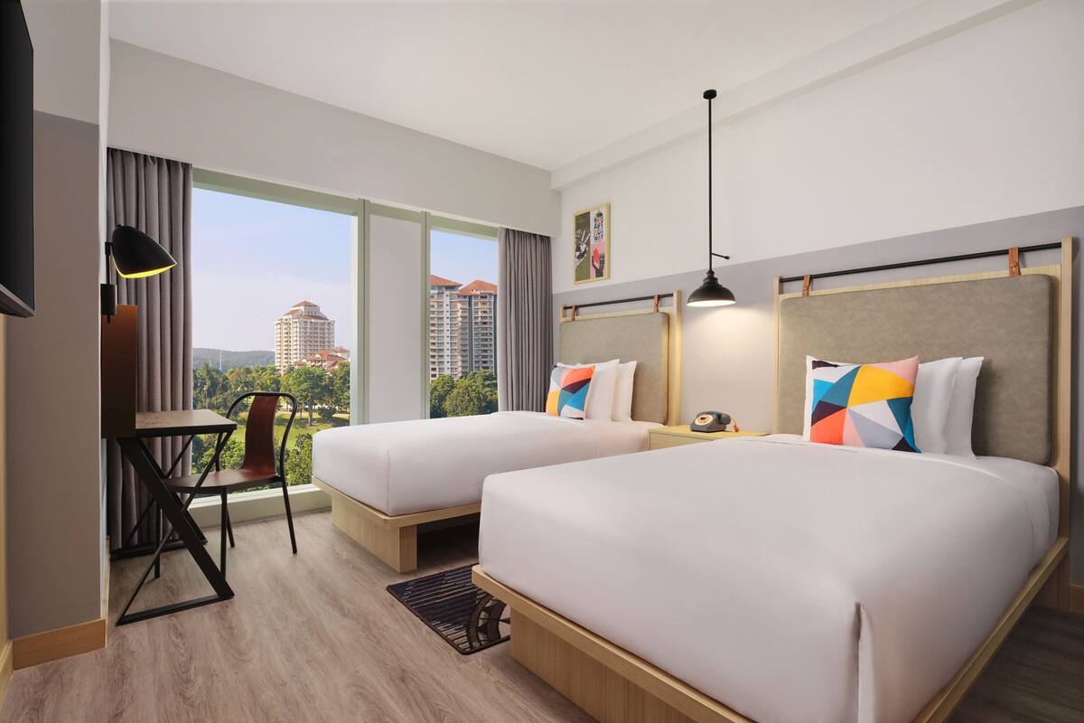 A hotel room with two beds, a desk, and a chair.