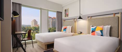 A hotel room with two beds, a desk, and a chair.
