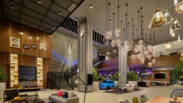 Un vestíbulo amplio con diseño moderno, que incluye una zona de estar amplia, una escalera y diversos elementos de iluminación.
