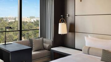 Une chambre d’hôtel avec une grande fenêtre, un canapé, un lit et une table de chevet.