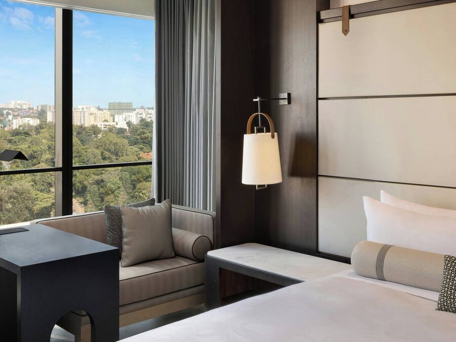 Une chambre d’hôtel avec une grande fenêtre, un canapé, un lit et une table de chevet.