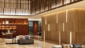 A spacious lobby with a high ceiling, modern furniture, and a large wooden panel wall.