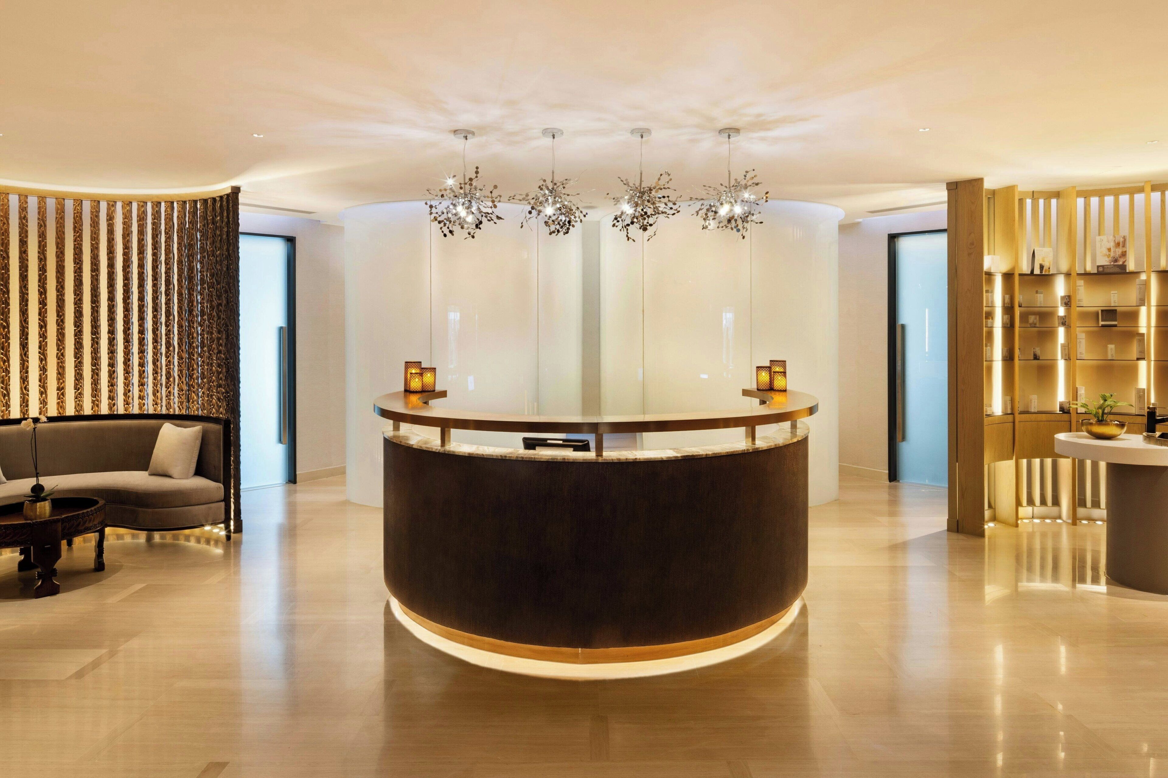A modern reception area with a central desk, a sofa, and a decorative wall with vertical elements.