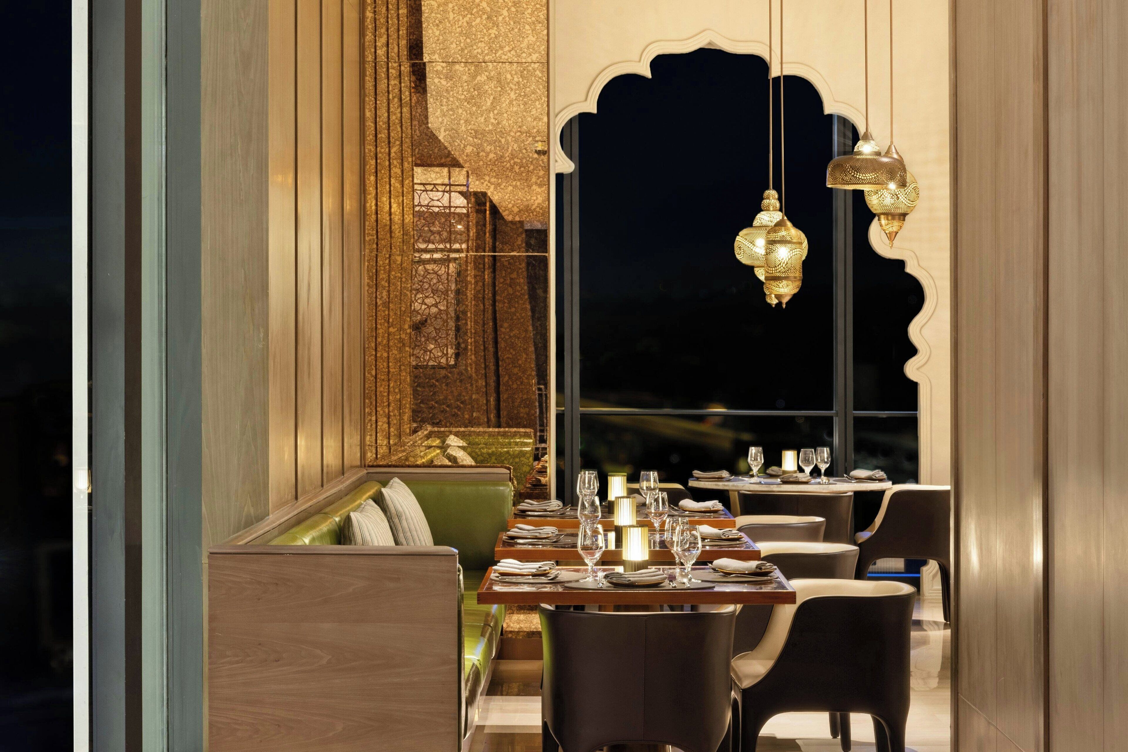 A restaurant with a cozy seating area, a high ceiling, and hanging decorative lights.