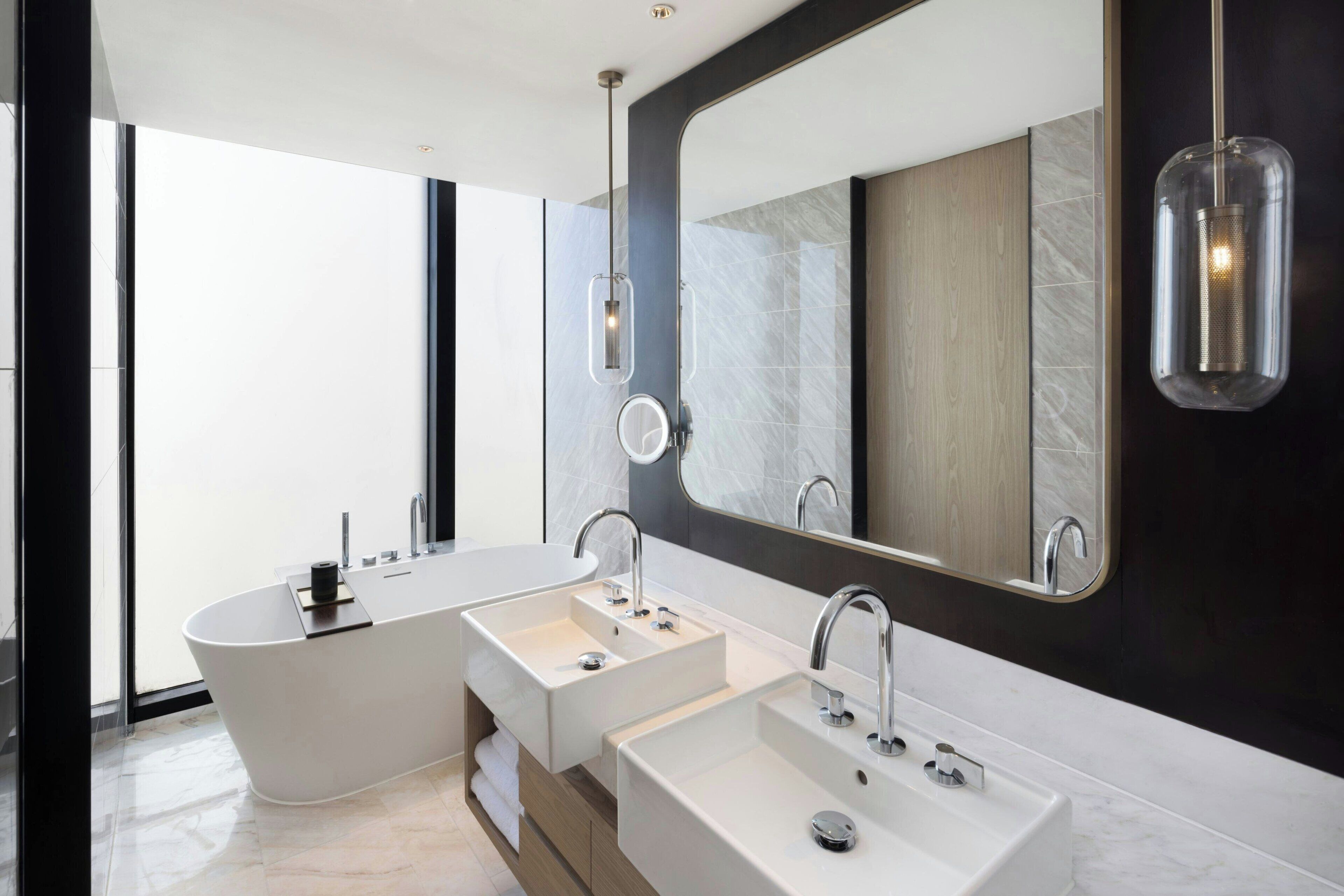 Une salle de bain moderne avec une baignoire sur pieds, deux vasques et un grand miroir.