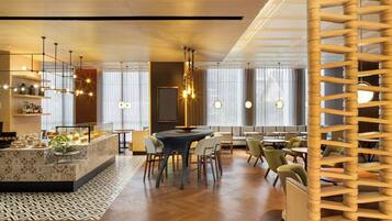 Un comedor moderno con una isla central, diversas opciones de asientos e iluminación colgante.