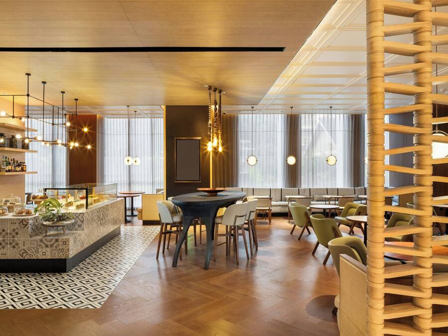 Un comedor moderno con una isla central, diversas opciones de asientos e iluminación colgante.