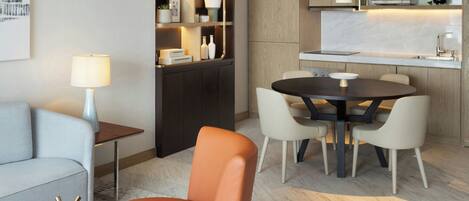 A modern living room with a sofa, a round table with chairs, a coffee table, a lamp, a bookshelf, and a kitchen area with a countertop and cabinets.