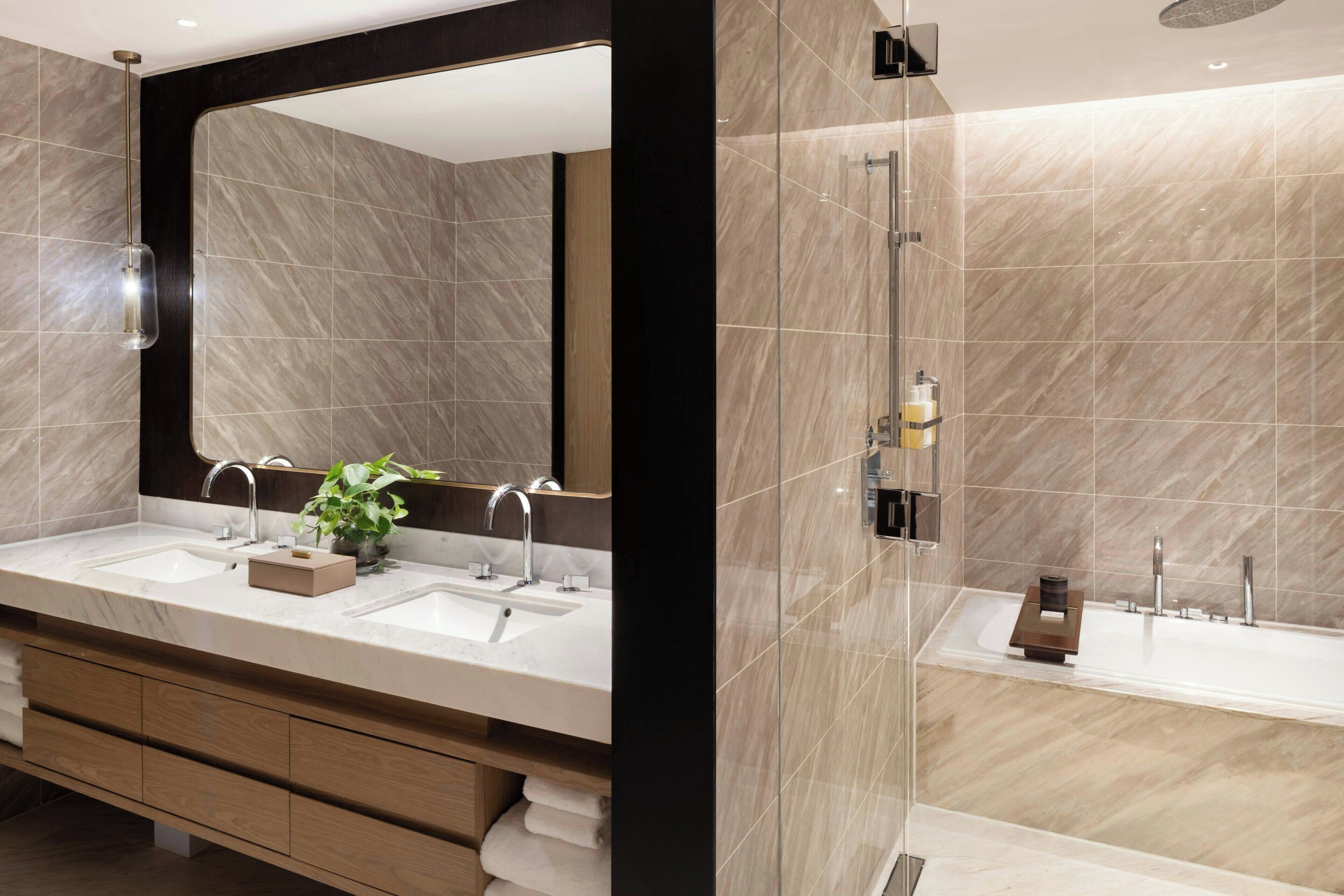 A modern bathroom with two sinks, a large mirror, and a glass-enclosed shower area.