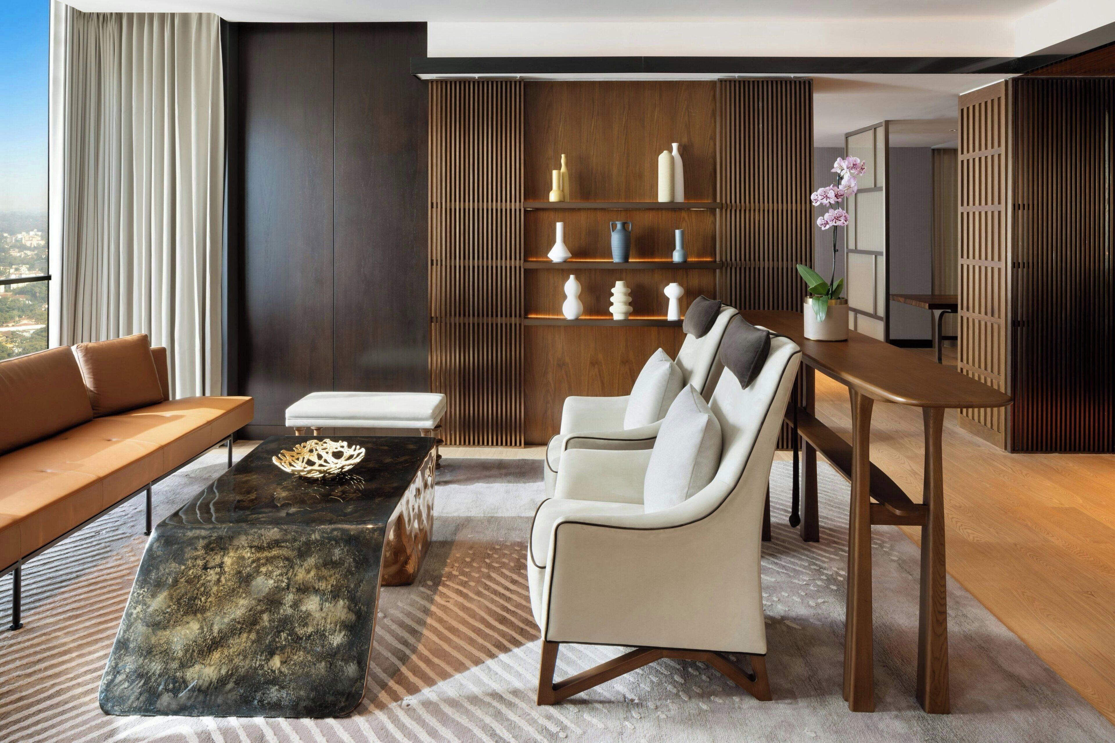A modern living room with a sofa, a coffee table, a chair, and a wooden bookshelf.