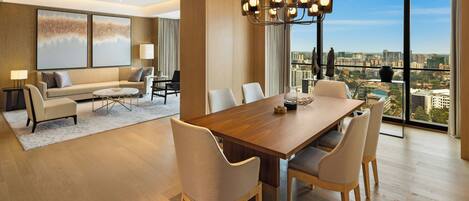 A modern living room with a dining area, large windows, and a city view.