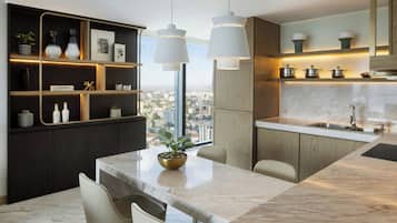 A modern kitchen with a marble countertop, pendant lights, and a city view.