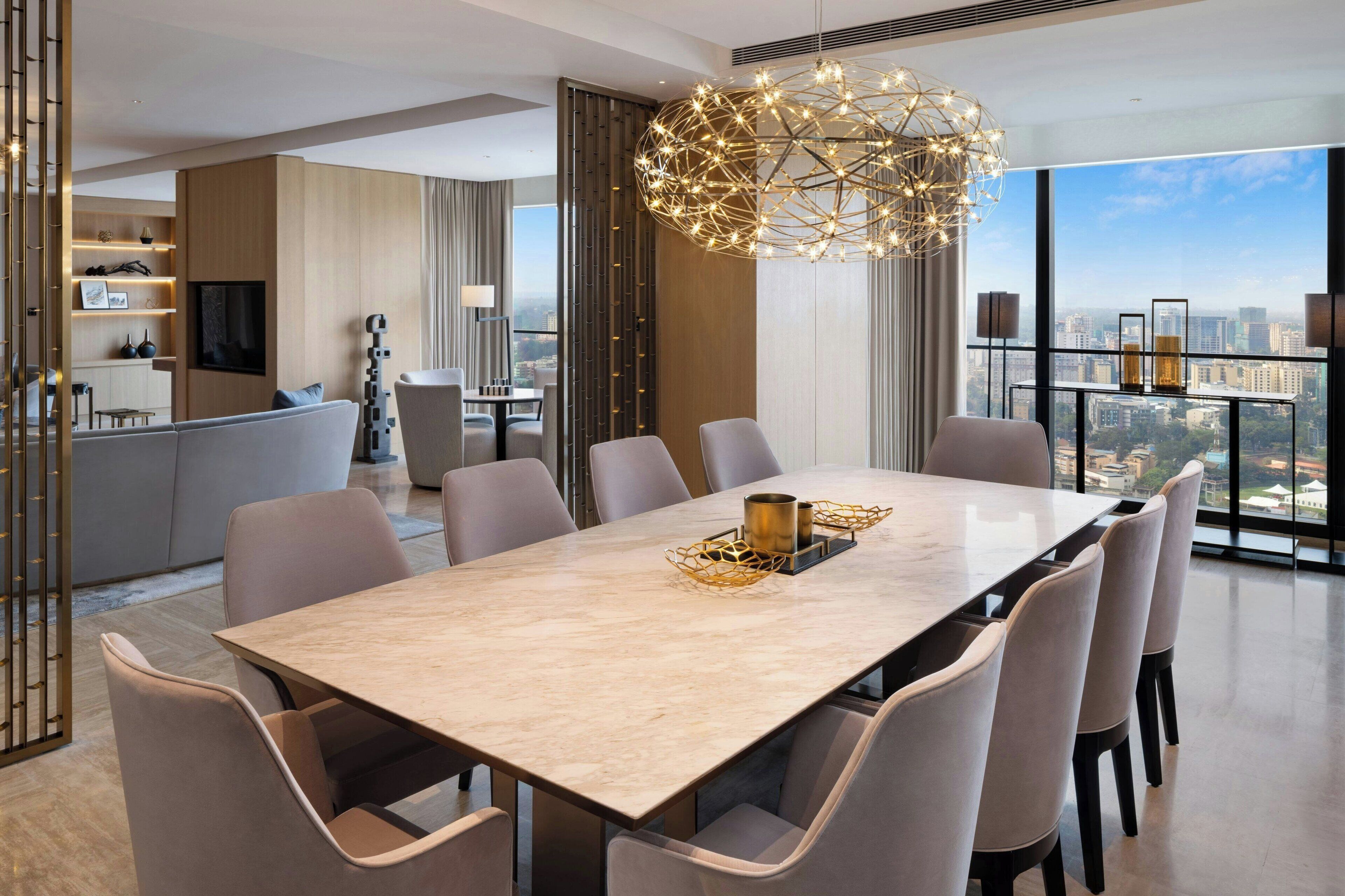 A modern dining area with a marble table, six chairs, and a decorative chandelier.