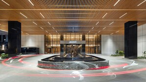 A modern hotel lobby with a central fountain, a wooden ceiling, and a large glass entrance. - JW Marriott Hotel Nairobi (Nairobi)