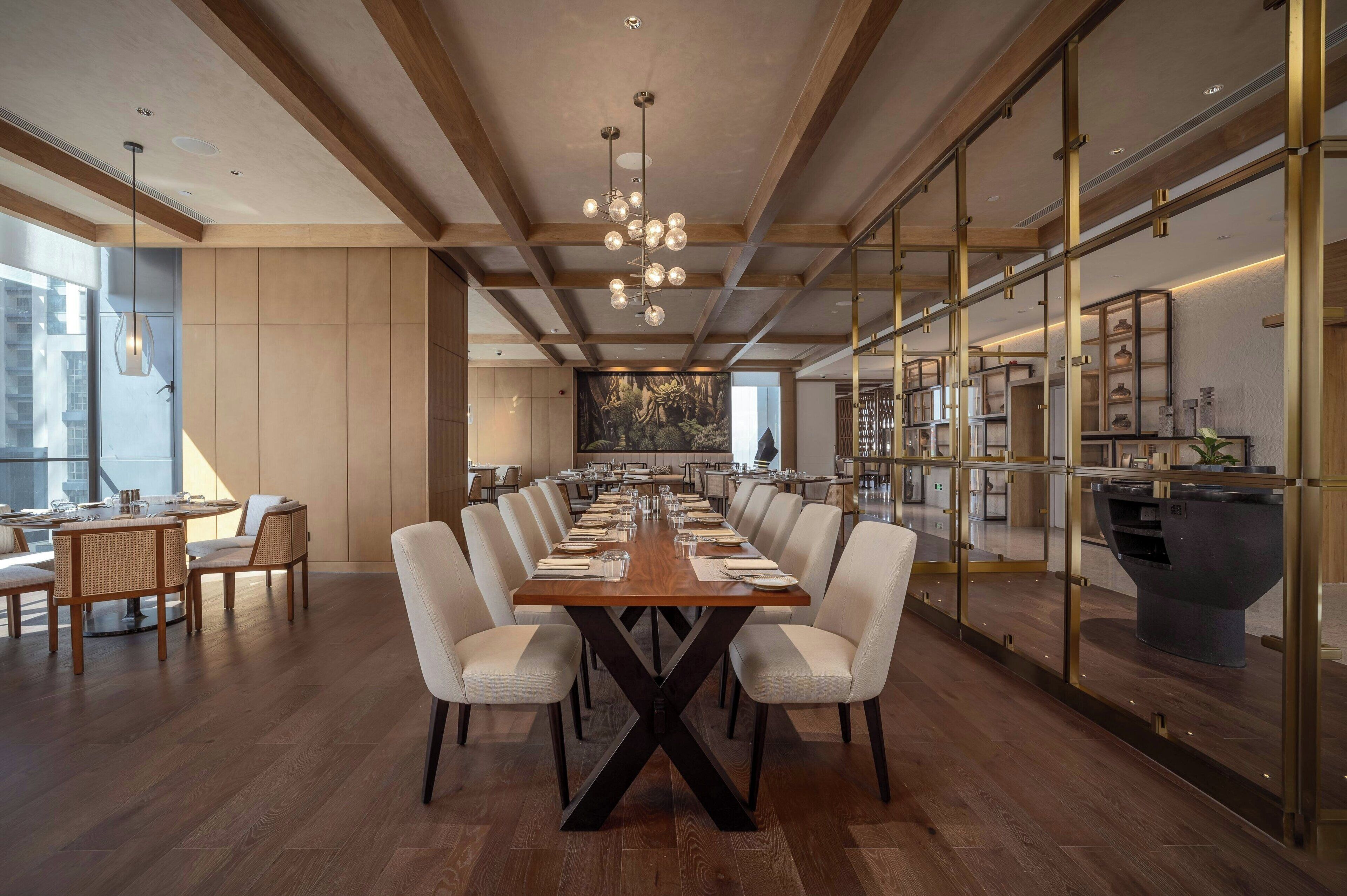A modern conference room with a long table, white chairs, and a chandelier.