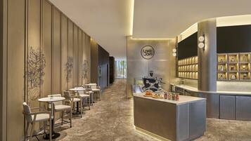 A modern cafe with a long counter, several round tables, and chairs.