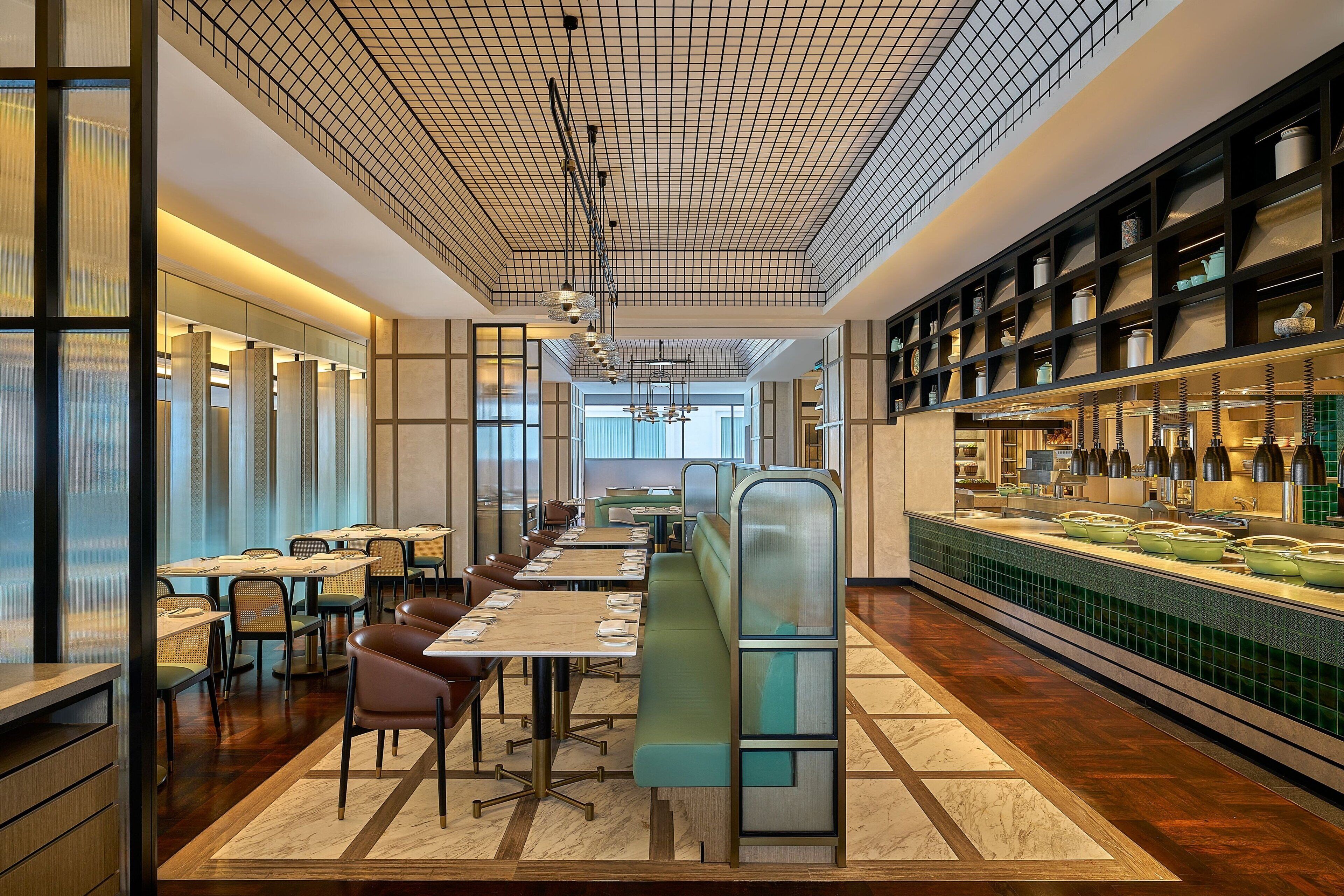 A modern restaurant interior with long communal tables, individual booths, and a bar area with shelves of bottles.