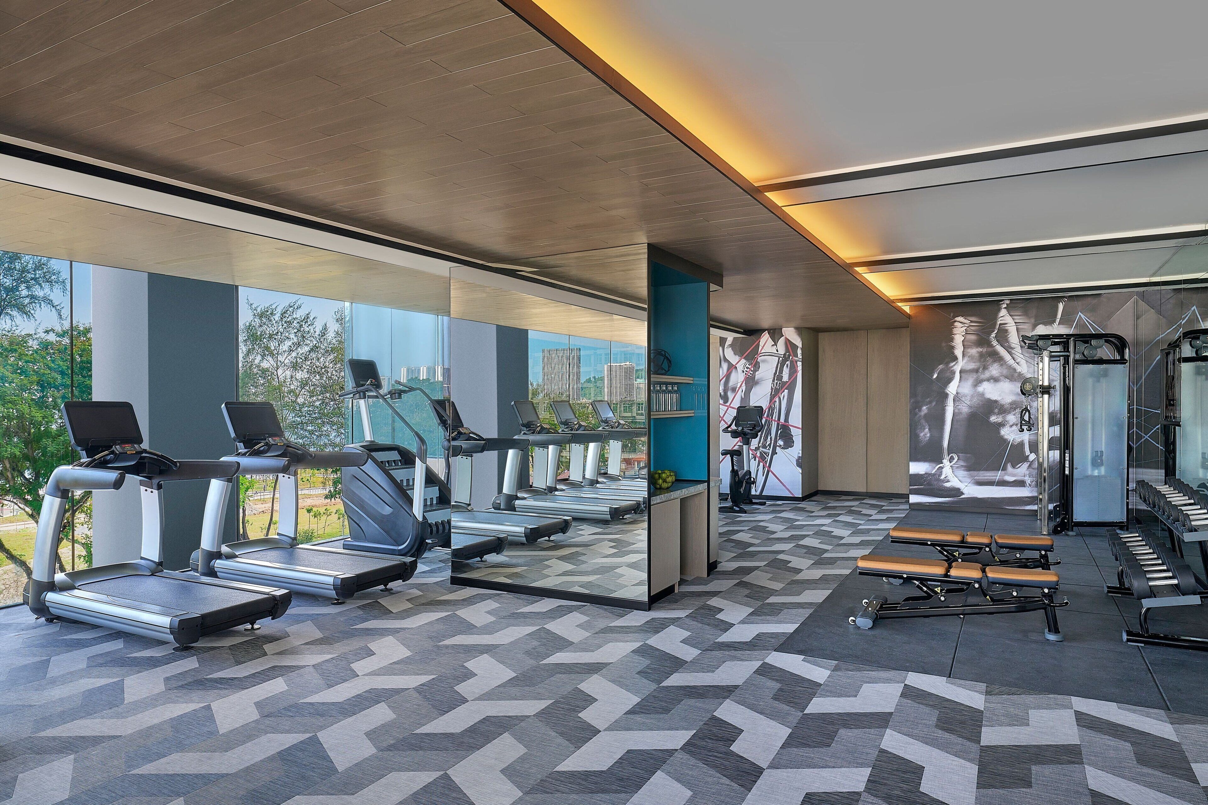 A modern gym with treadmills, stationary bikes, and benches.