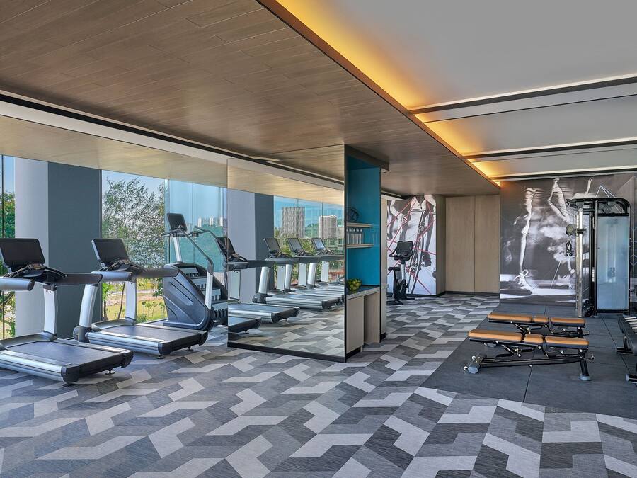 A modern gym with treadmills, stationary bikes, and benches.