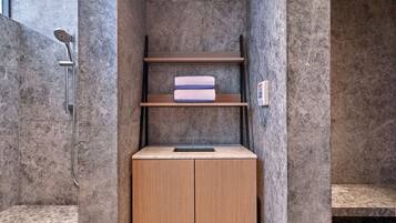 Een badkamer met een douche, een houten kastje en een plank met handdoeken.