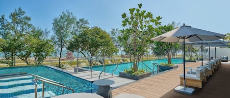 A poolside area with lounge chairs, a small table, and a large umbrella.