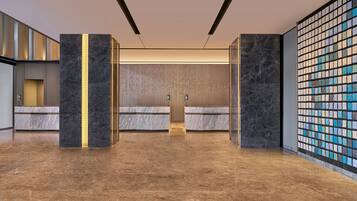 Een moderne lobby met marmeren vloeren, een receptiebalie en een decoratieve wand met een mozaïekpatroon.