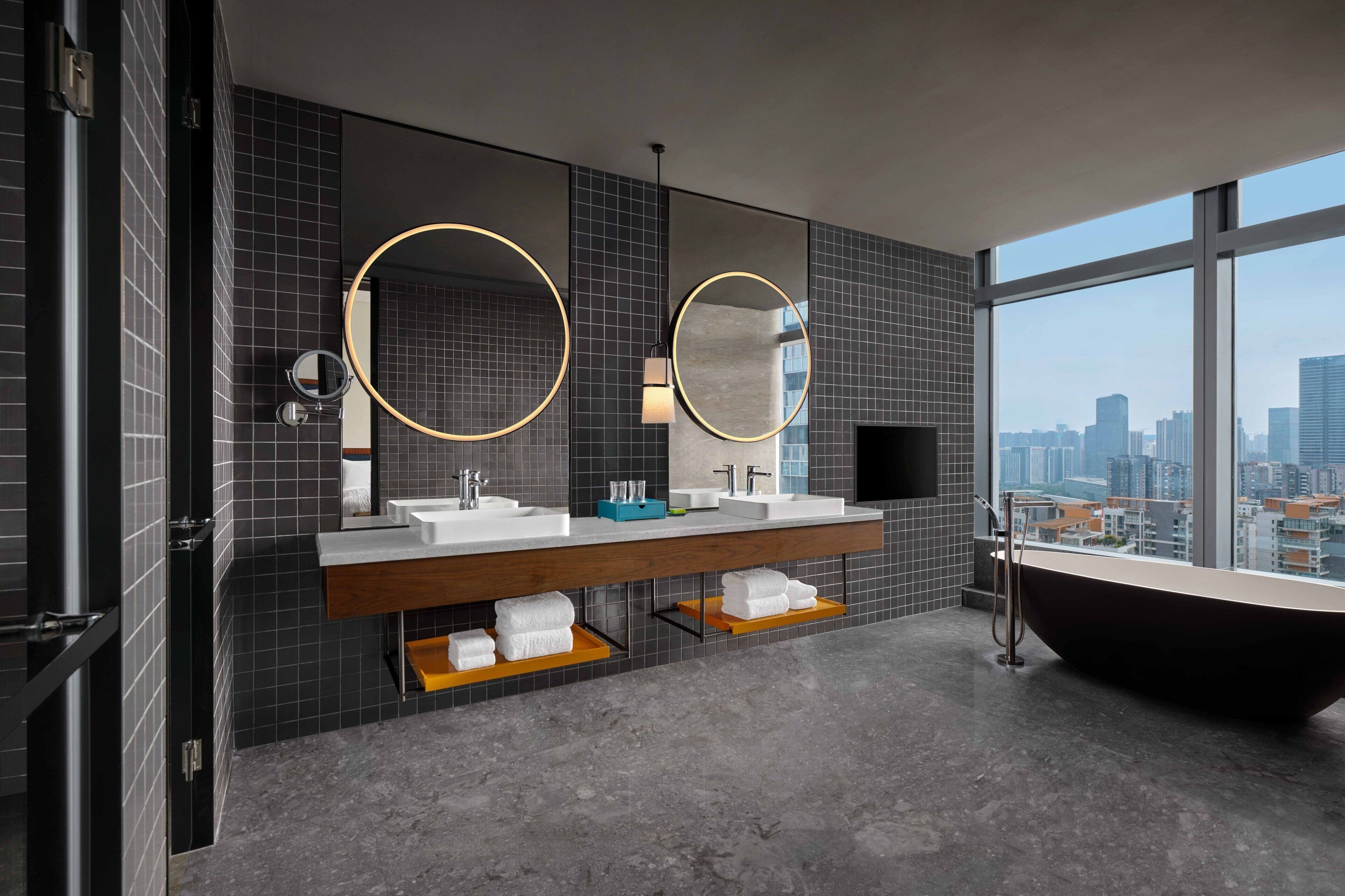 Un baño moderno con dos lavamanos, un espejo grande y una bañera independiente.