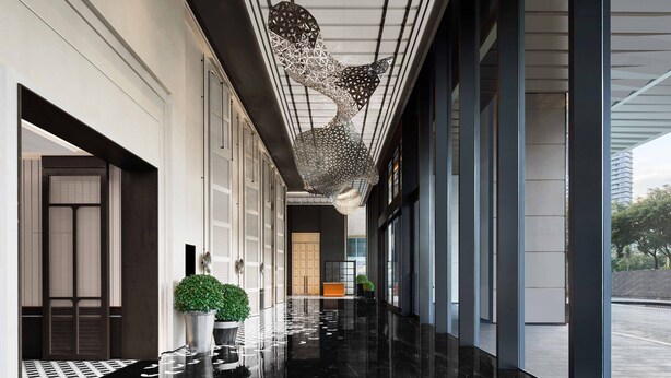 A modern hotel corridor with a reflective black floor, a large decorative metal sculpture, and potted plants. - Le Méridien Shenzhen, Bao'An (Shenzhen)