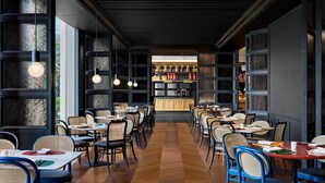 A restaurant with a long wooden floor, black and white patterned walls, and hanging pendant lights. Tables are set with chairs, and a bar area is visible in the background. - Le Méridien Shenzhen, Bao'An (Shenzhen)
