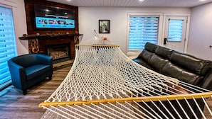 Ein Wohnzimmer mit einer Hängematte, einem Kamin, einem Fernseher und einem Ledersofa.