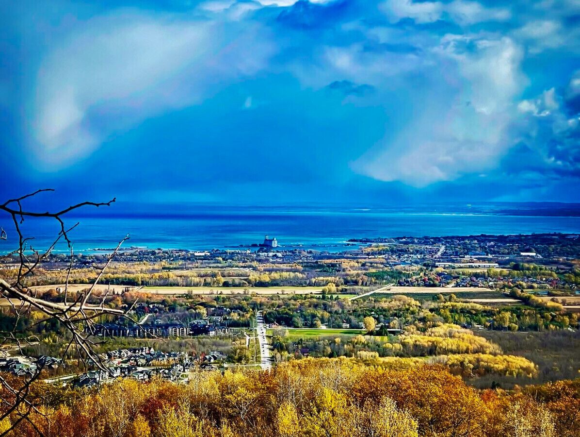 Vista panorámica de un pueblo costero con cielo despejado, un río y una combinación de edificios residenciales y comerciales.