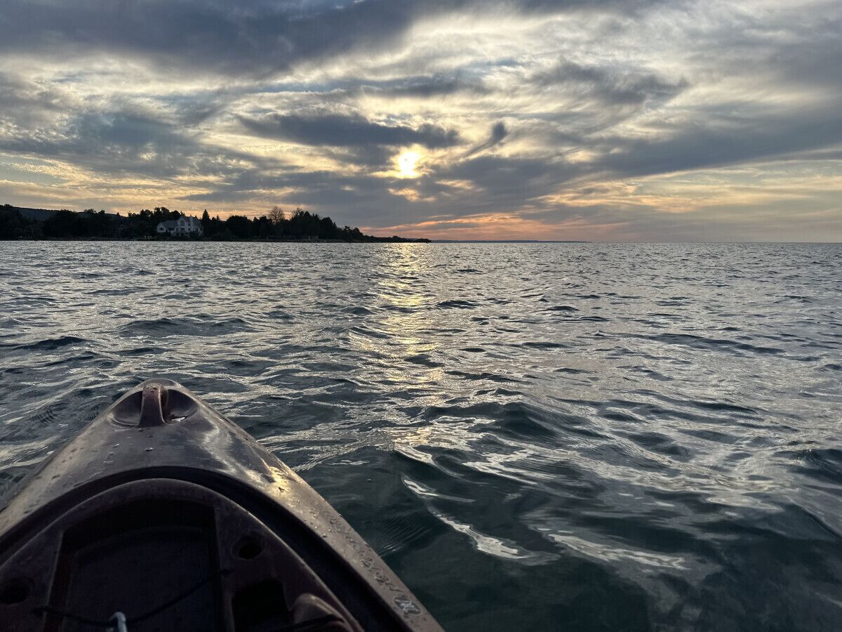 A kayak on a body of water with a sunset in the background.
