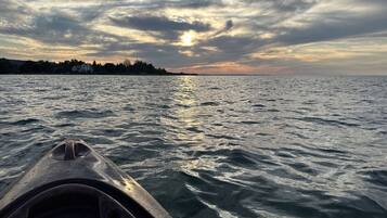 A kayak on a body of water with a sunset in the background.