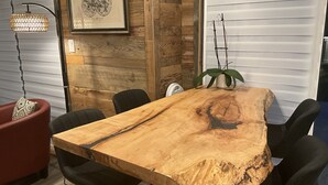 Una mesa de comedor de madera con sillas, una silla roja, un mapa enmarcado y un colgador de techo.