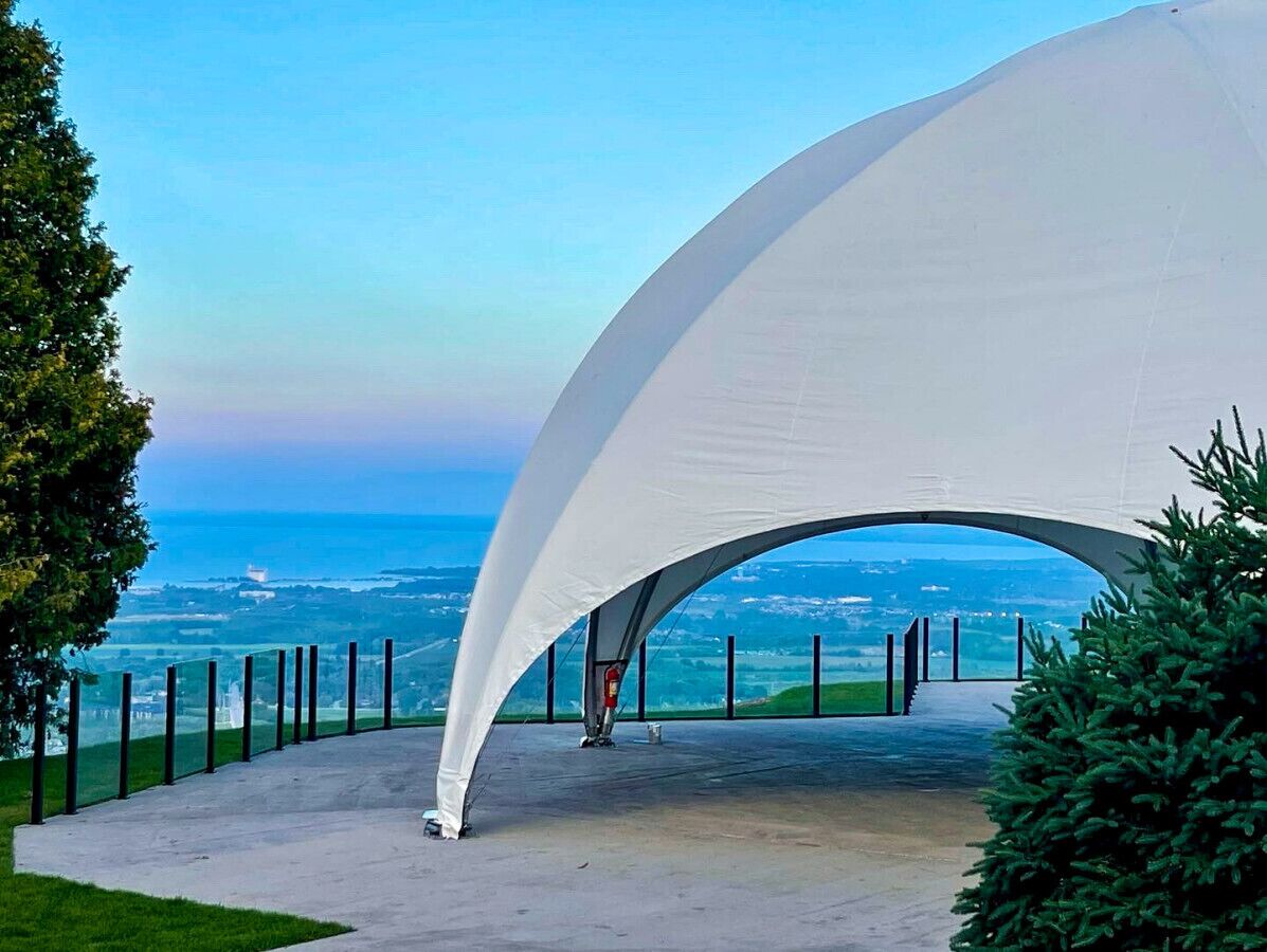 A white tent-like structure with a clear view of the ocean and distant landscape.