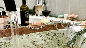Casa de banho com toucador de madeira, uma garrafa de vinho e um copo de vinho tinto.