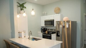 A modern kitchen with a central island, stainless steel appliances, and pendant lighting. - Paradise Palms - Walk to Beach! (Corpus Christi)