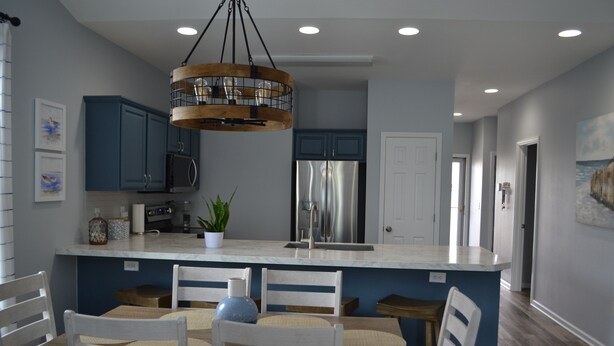 Eine moderne Küche mit blauen Schränken, einem Edelstahlkühlschrank und einer Holztheke mit Sitzgelegenheiten.