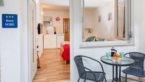 A hotel room with a kitchenette, a dining area with a table and chairs, a mirror, and a sign indicating the room type. - BIS Studio Apartment 3 (Dubrovnik)