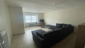 A living room with a sectional sofa, a small round table, and a television. - House 10/12pers town center 5mn from Puy Du Fou "AU COEUR DU BOURG (Chanverrie)