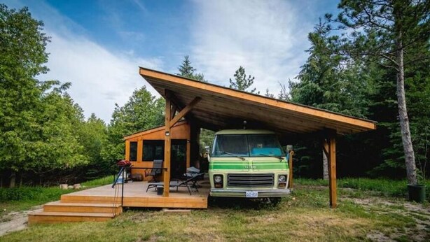 A vintage green bus converted into a rustic cabin with a wooden deck and outdoor seating. - Unique Glamping RV on 100 acres 1 hr from Toronto (Blackstock)
