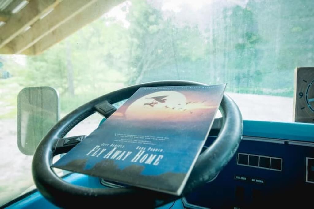 Een boek met de titel 'Fifty Away Home' op een stuur in een voertuig.