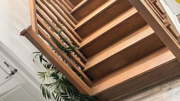 Eine Holztreppe mit modernem Design, inklusive einem geometrischen Muster und einer Pflanze unten.