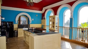 A kitchen with a large island, blue walls, and arched windows. - Stunning, historic holiday apartment  (Criccieth)