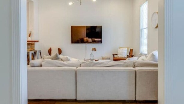 Una sala de estar moderna con un sofá modular, un televisor de pantalla plana y una lámpara de techo.